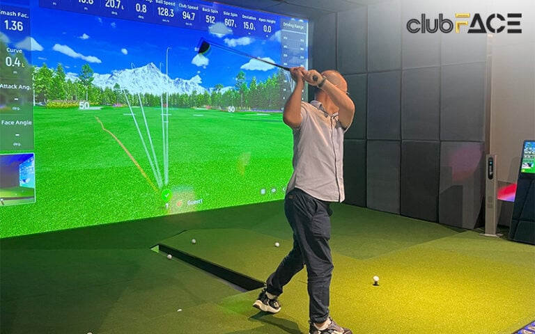 A man takes a shot in an indoor golf simulator