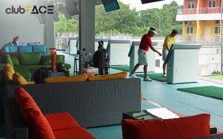 Golfers practising at a driving range bay with shared lounge