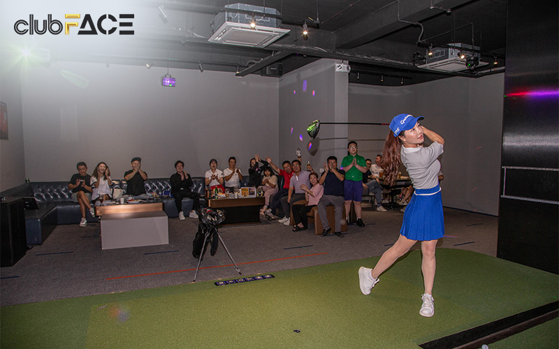People cheering on a woman using a golf simulator