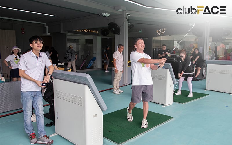 People enjoying a game of indoor golf with digital swing analysis screens.