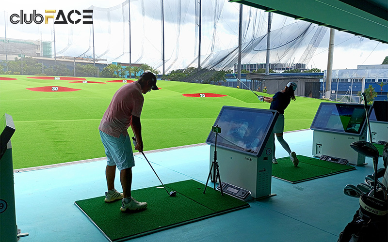 people practicing golf shots on the driving range.